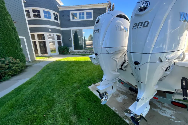 Slide: The Image of Twin Yamaha 200 outboard motors on a 2027 Pursuit S 268 Sport boat, near a modern building. - 2