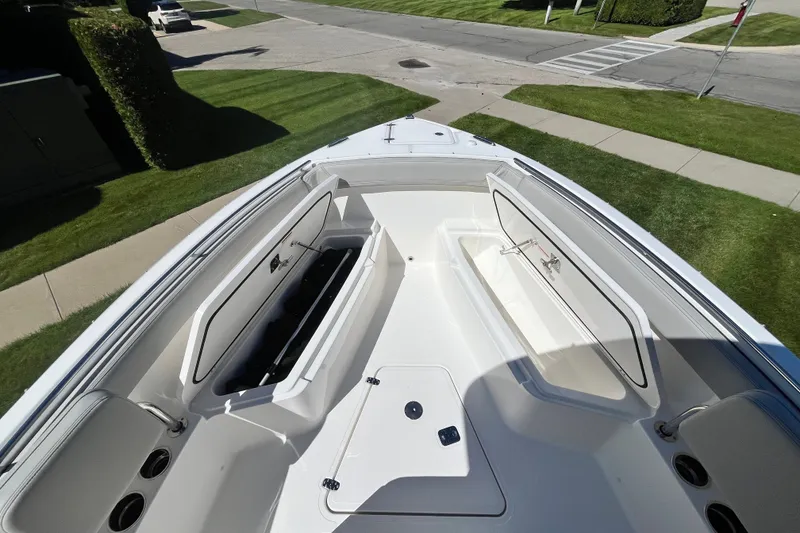 Slide: The Image of 2027 Pursuit S 268 Sport boat interior with open storage compartments, parked on a grassy area. - 8
