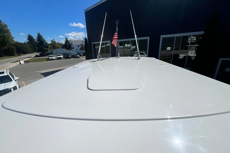 Slide: The Image of 2027 Pursuit S 268 Sport boat rooftop with American flag, parked outdoors. - 12