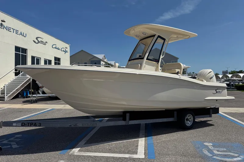 Slide: The Image of 2027 Scout 220 XSF boat on trailer outside dealership under clear blue sky. - 3