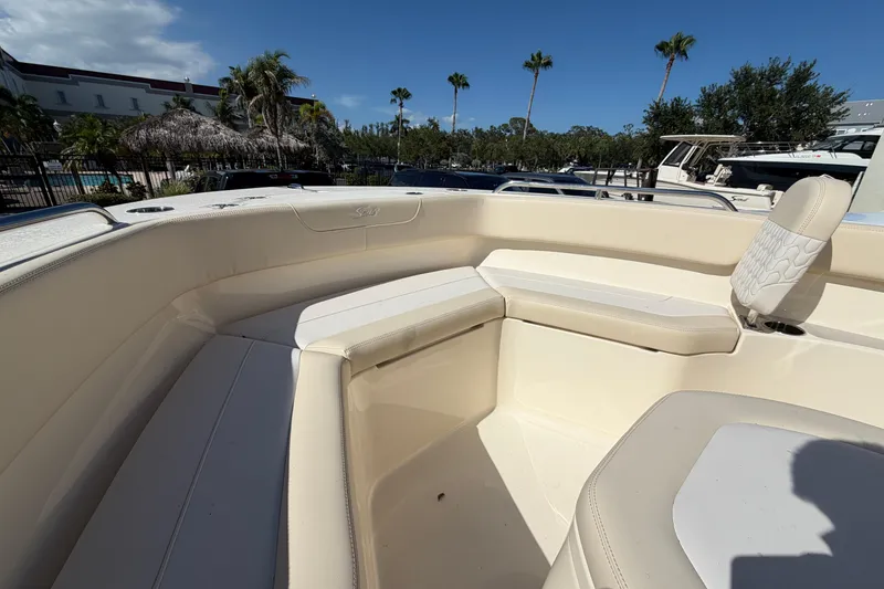 Slide: The Image of 2027 Scout 220 XSF boat interior with beige seating, palm trees, and blue sky background. - 23