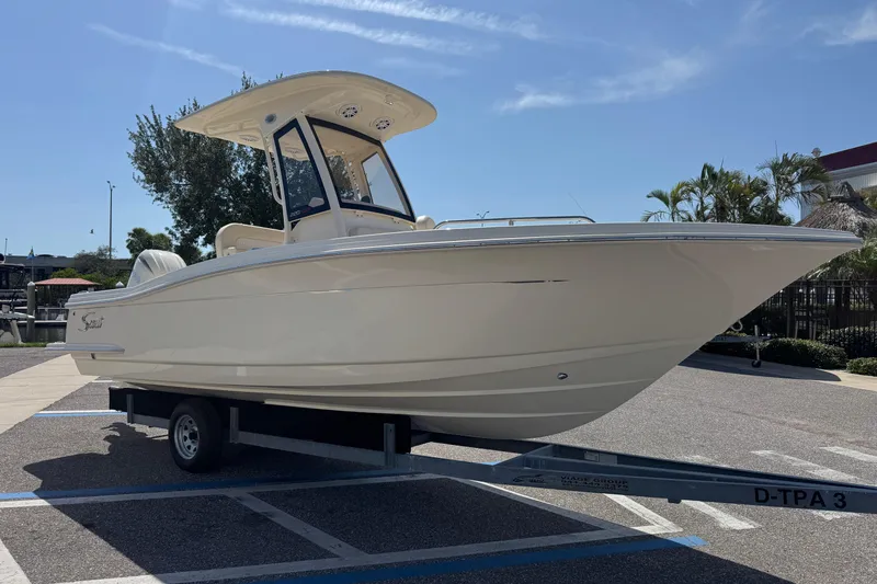 Slide: The Image of 2027 Scout 220 XSF boat on trailer in sunny parking lot. - 2
