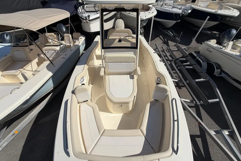 Slide: The Image of 2027 Scout 220 XSF boat with spacious seating and sleek design in a marina setting. - 26