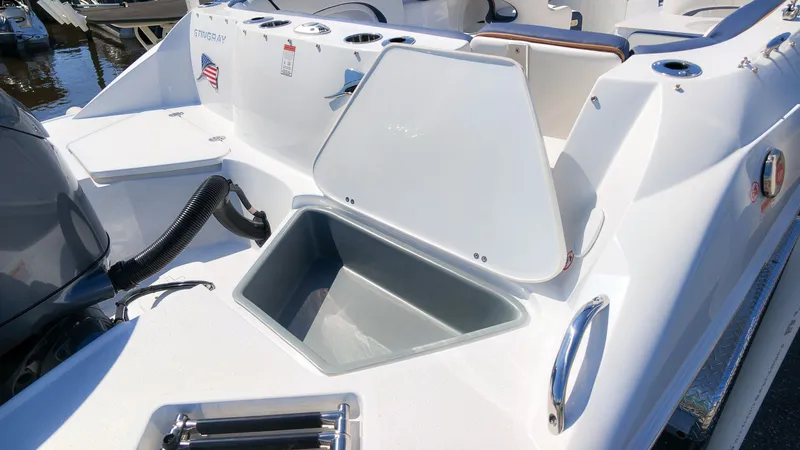 Slide: The Image of Stingray 231 DC 2027: Open storage compartment on a white boat, surrounded by water. - 4