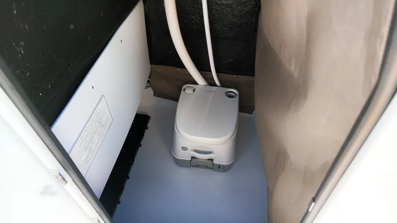 Slide: The Image of The image shows a compact toilet inside a boat, surrounded by simple walls. - 14