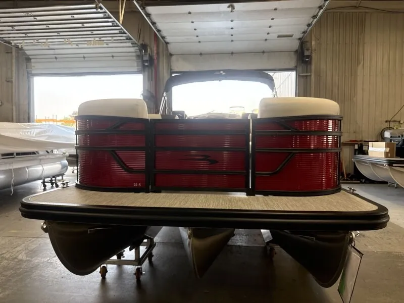 Slide: The Image of A Bennington 22 S1 Stern Radius pontoon boat is in a warehouse. It features red side panels. - 3