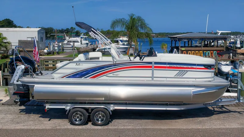 Slide: The Image of A 2027 Bennington 22 M Swingback pontoon boat on a trailer in a marina area. - 29