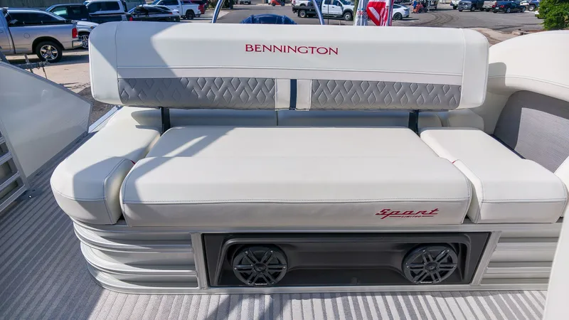 Slide: The Image of The image shows a luxurious bench seat on a Bennington 22 M Swingback boat, featuring elegant upholstery and speakers. - 9
