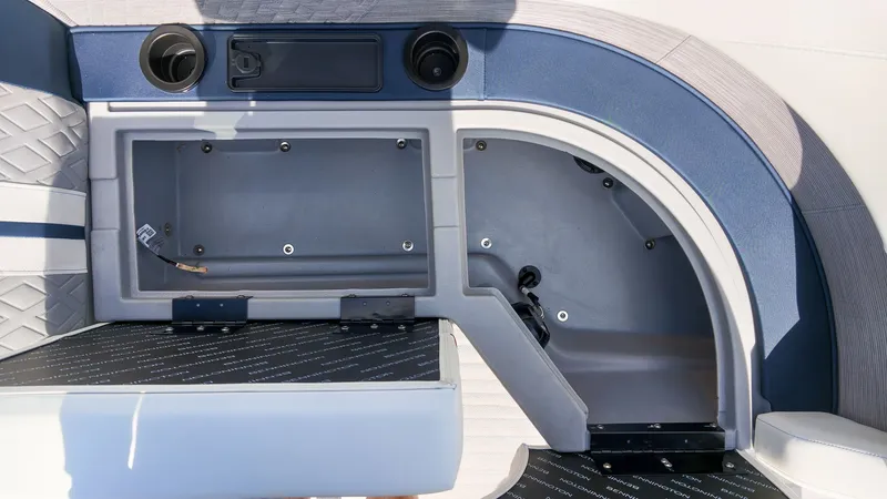 Slide: The Image of The image shows part of the interior of a 2027 Bennington 22 M Swingback boat with blue upholstery and an empty compartment. - 20