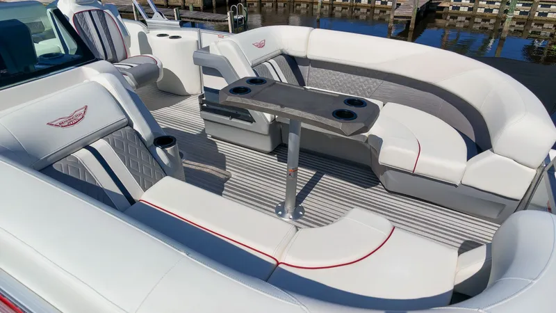 Slide: The Image of The image shows the interior of a 2027 Bennington 22 M Swingback. It features white upholstery with red accents and a table with cup holders. - 17