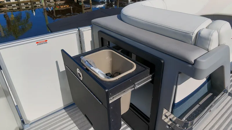 Slide: The Image of The image shows part of the interior of a Bennington 22 M Swingback boat with a built-in trash bin. - 13