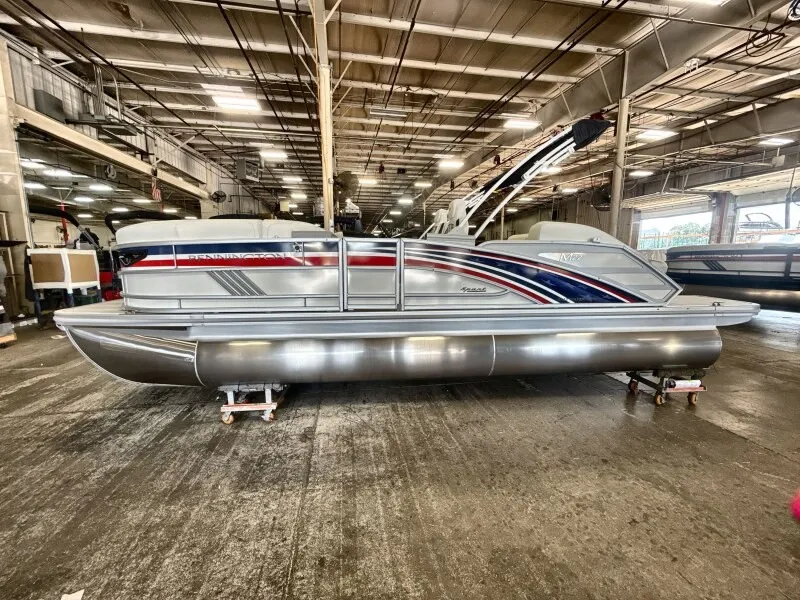 The Image of A 2027 Bennington 22 M Swingback pontoon boat is on stands in a warehouse. - 1