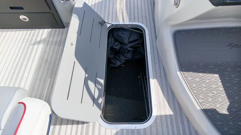 Slide: The Image of An open storage compartment on a boat with gray carpeting and a black cover inside. - 15