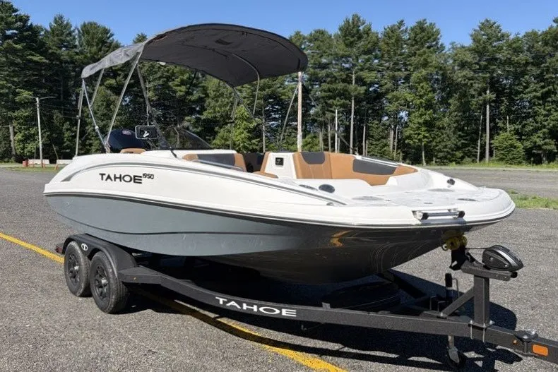 Slide: The Image of 2026 Tahoe 1950 boat on trailer, parked outdoors with trees in background. - 1