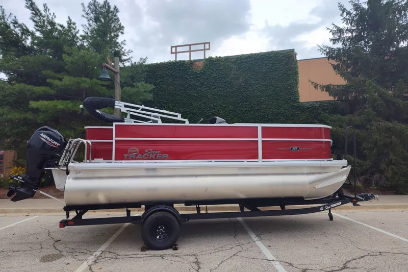 The Image of 2026 Sun Tracker Party Barge 18 DLX pontoon boat on trailer, parked outdoors. - 0