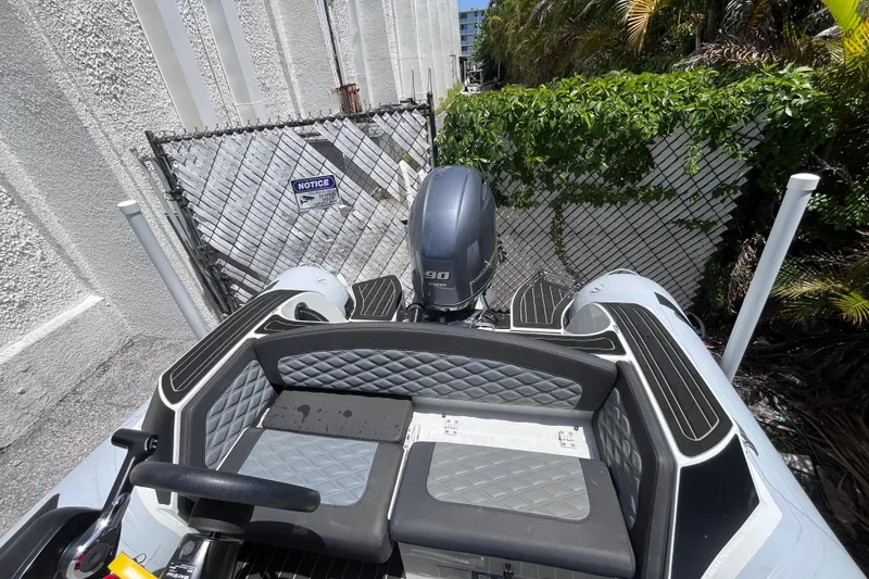 Slide: The Image of 2024 Highfield Sport 520 boat with Yamaha engine, parked near a fence and greenery. - 21