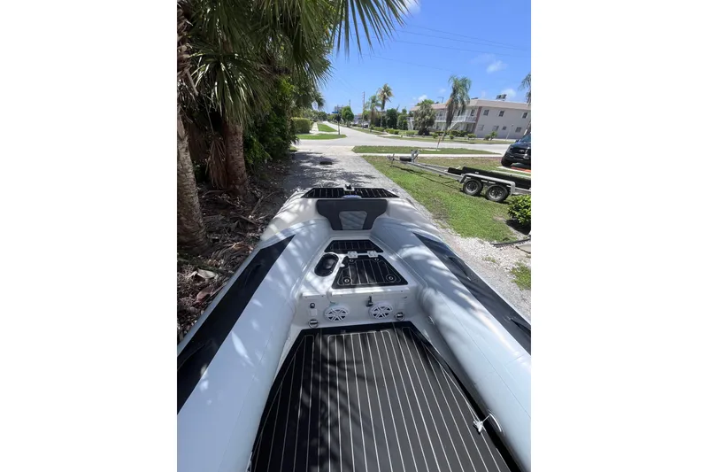Slide: The Image of 2024 Highfield Sport 520 boat on a sunny day, parked near palm trees and a trailer. - 14