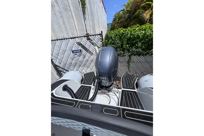 Slide: The Image of 2024 Highfield Sport 520 boat with Yamaha engine, parked near a fence and greenery. - 22