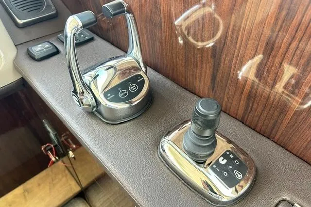 Slide: The Image of 2017 Sea Ray Sundancer 400 helm controls with polished levers and joystick on wood panel. - 36