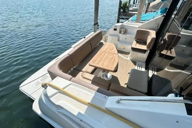 Slide: The Image of 2017 Sea Ray Sundancer 400 yacht with spacious seating and table, docked by the water. - 10
