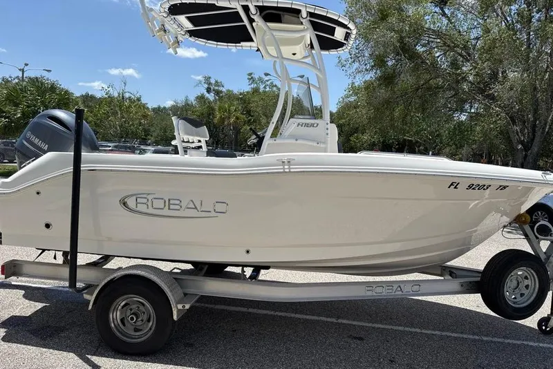 Slide: The Image of 2021 Robalo R180 Center Console boat on trailer, featuring Yamaha engine, parked outdoors. - 1