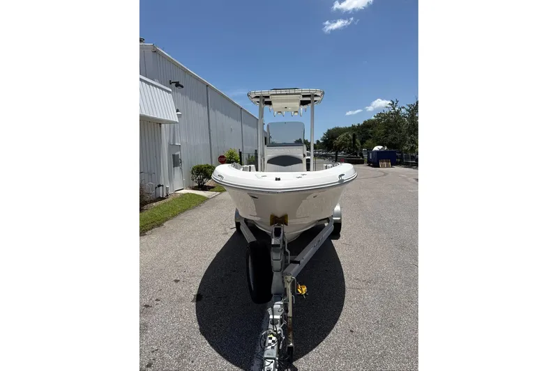 Slide: The Image of 2021 Robalo R180 Center Console boat on trailer, parked outdoors under clear sky. - 2