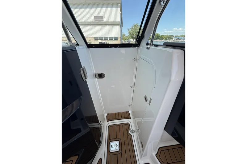 Slide: The Image of 2021 Pursuit DC 235 Dual Console interior with teak flooring and white paneling. - 7