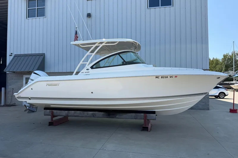 The Image of 2021 Pursuit DC 235 Dual Console boat displayed outdoors on a stand. - 0