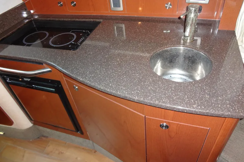 Slide: The Image of 2013 Sea Ray Sundancer 330 galley with sink, stovetop, and wooden cabinetry. - 43