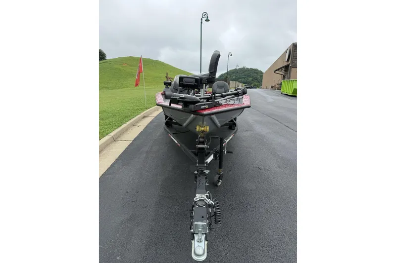 Slide: The Image of 2024 Tracker Pro Team 175 TF boat on trailer, parked on asphalt near grassy hill. - 6
