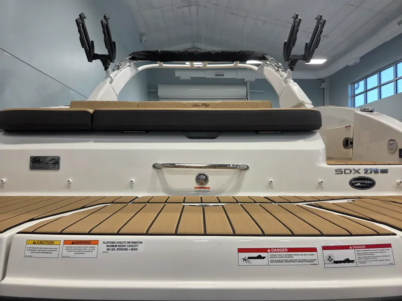 Slide: The Image of The image shows the rear of a Sea Ray SDX 270 Surf boat with a wood deck and cushioned seats. - 7