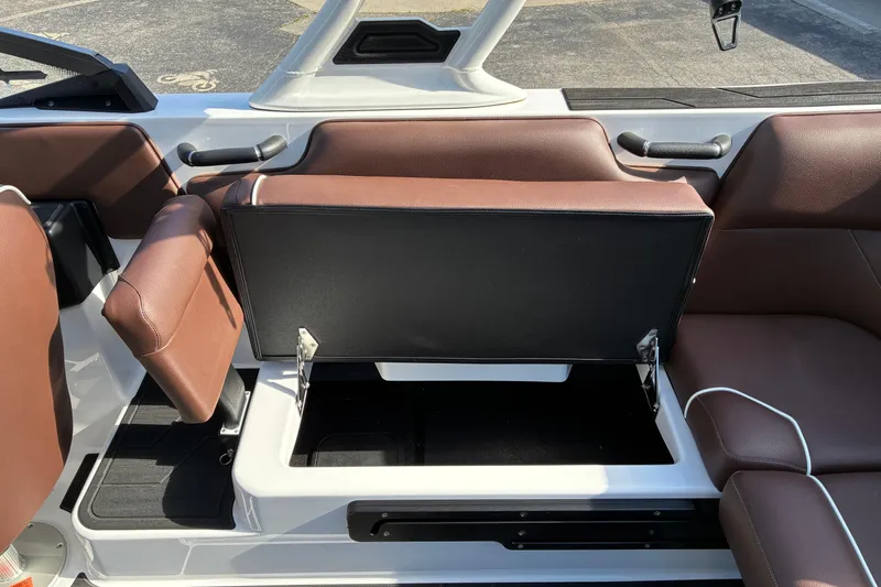 Slide: The Image of 2025 Moomba Max boat interior with open storage compartment and brown seating. - 22