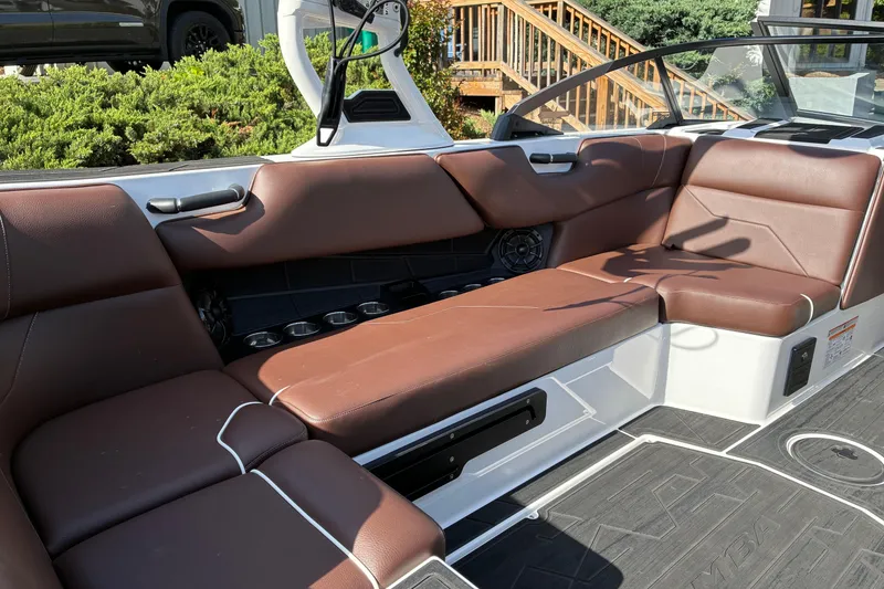Slide: The Image of 2025 Moomba Max boat interior with brown leather seating and cup holders. - 18