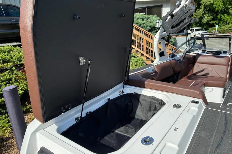 Slide: The Image of 2025 Moomba Max boat interior with open storage compartment and brown seating. - 12