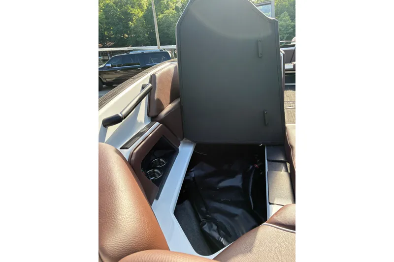 Slide: The Image of 2025 Moomba Max boat interior storage compartment with brown seating and cup holders. - 38