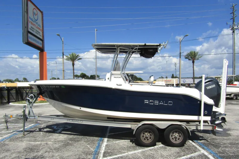 The Image of 2018 Robalo R202 Explorer boat on trailer, parked outdoors under clear sky. - 0