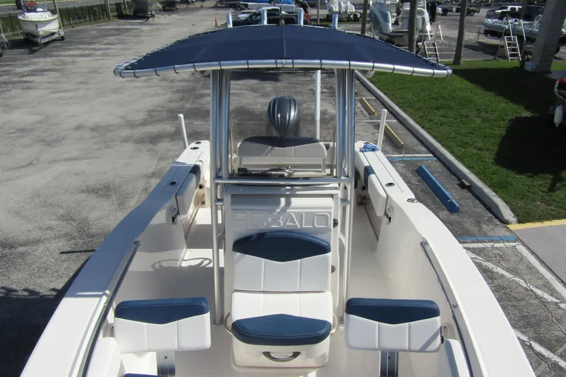 Slide: The Image of 2018 Robalo R202 Explorer boat with blue canopy and seating, parked on concrete. - 20