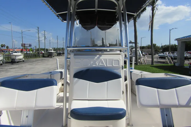Slide: The Image of 2018 Robalo R202 Explorer boat interior with blue and white seating, parked outdoors. - 17