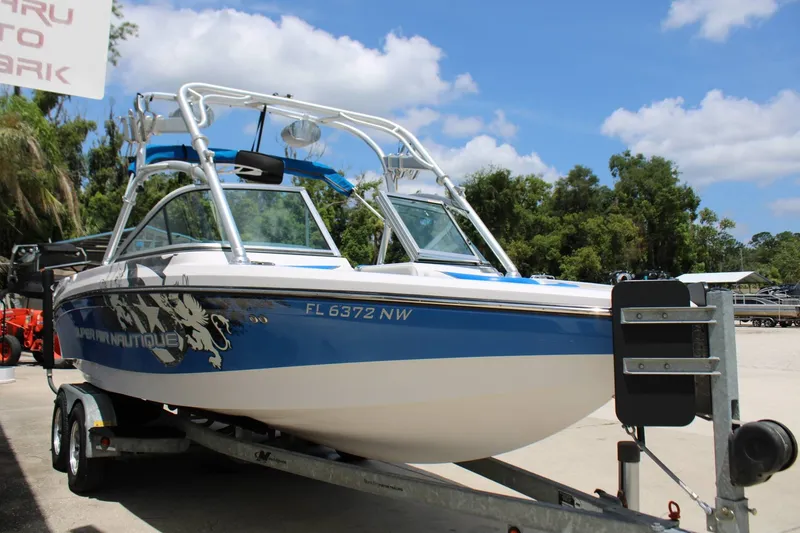 Slide: The Image of A blue and white 2008 Nautique 210 Team boat on a trailer, surrounded by trees. - 4