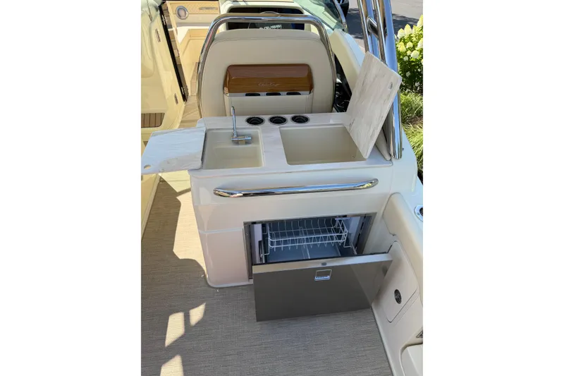 Slide: The Image of 2027 Chris-Craft Calypso 28 boat interior with sink, countertop, and open drawer refrigerator. - 29