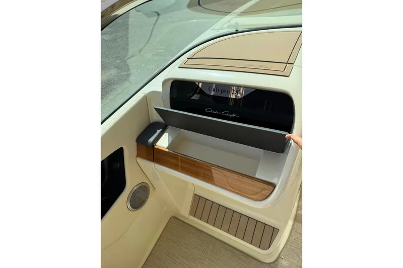 Slide: The Image of 2027 Chris-Craft Calypso 28 boat interior with open storage compartment and elegant wood accents. - 23