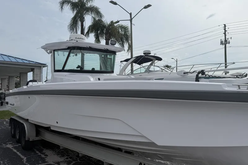 Slide: The Image of 2025 Axopar 29 CCX boat on trailer, parked outdoors near palm trees. - 0