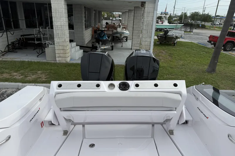 Slide: The Image of 2025 Axopar 29 CCX boat with dual outboard motors, docked near a showroom. - 7