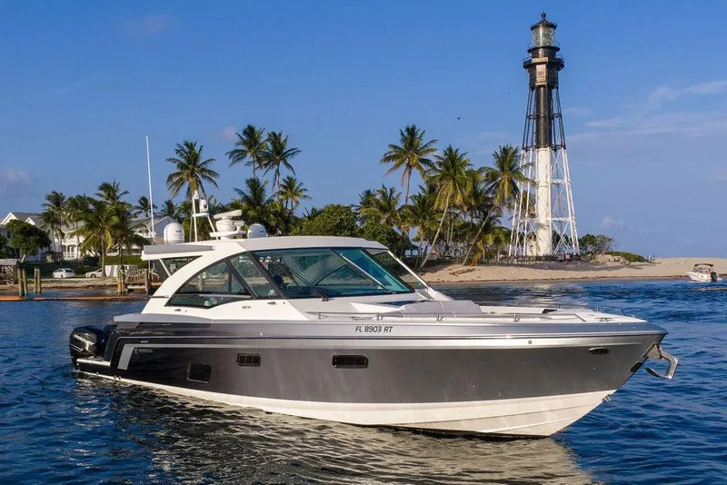 Slide: The Image of The 2018 Formula 430 Super Sport Crossover cruises on calm waters near a lighthouse and palm trees. - 13