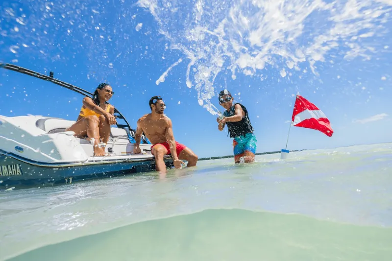 Slide: The Image of Three people enjoy the water beside a Yamaha 195S boat under a blue sky. - 5