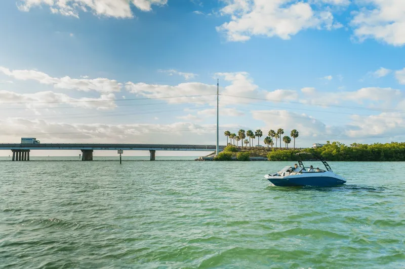 Slide: The Image of A 2024 Yamaha 195S boat cruising on sunny waters with a bridge in the background. - 30