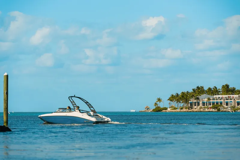 Slide: The Image of A 2024 Yamaha 195S boat cruising on calm waters near a tropical coastline. - 10