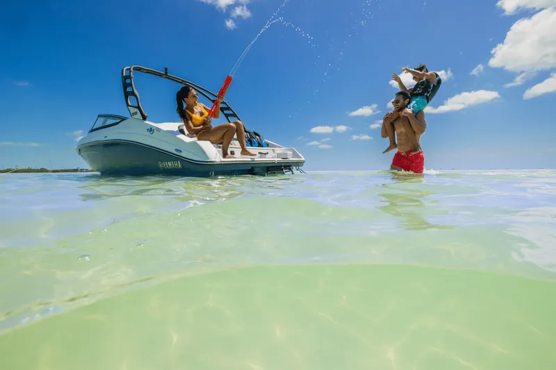 Slide: The Image of A 2024 Yamaha 195S on clear water. A woman sprays water while a man carries a child. - 6