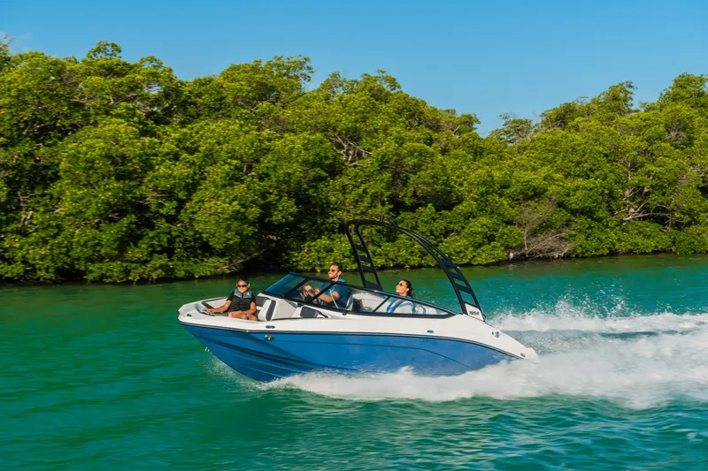 Slide: The Image of A 2024 Yamaha 195S boat speeds across turquoise water, surrounded by lush greenery. - 34