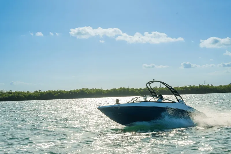 Slide: The Image of A 2024 Yamaha 195S boat speeds across the water under a clear blue sky. - 2